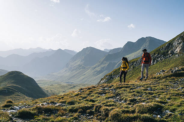 istock Couple hike across mountain meadow at sunrise 2206235787