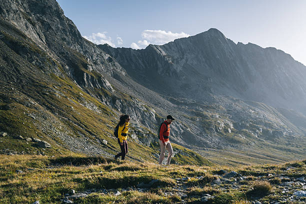 istock Couple hike across mountain meadow at sunrise 2206235810