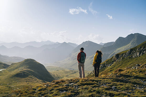 istock Couple hike across mountain meadow at sunrise 2206235842