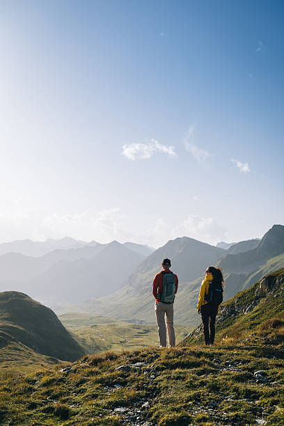 istock Couple hike across mountain meadow at sunrise 2206235845