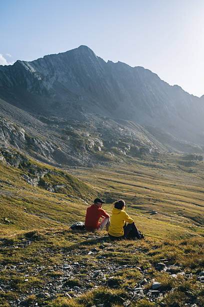 istock Hikers sit in mountain meadow at sunrise 2206235864