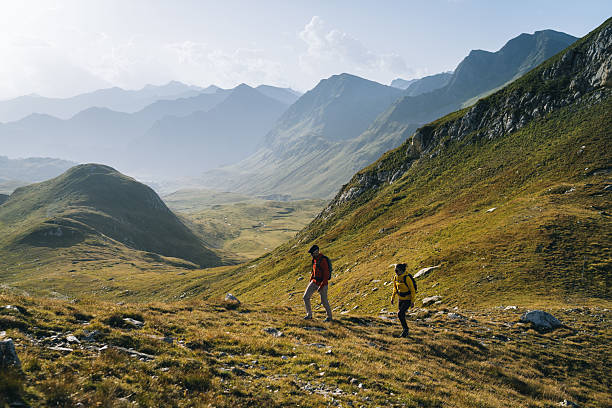 istock Couple hike across mountain meadow at sunrise 2206235873