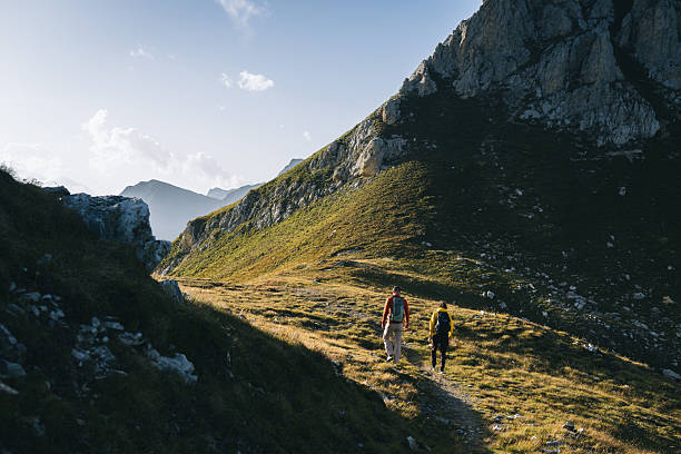 istock Couple hike across mountain meadow at sunrise 2206235875