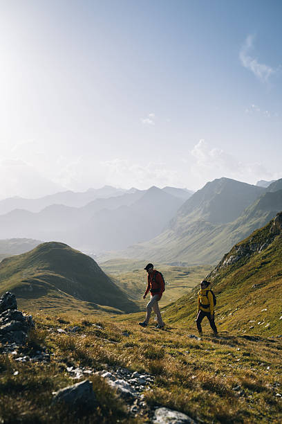 istock Couple hike across mountain meadow at sunrise 2206235887
