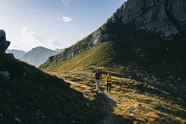 istock Couple hike across mountain meadow at sunrise 2206235935