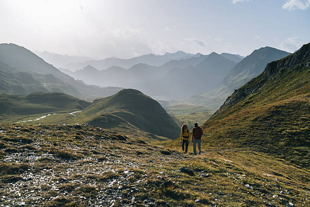 istock Couple hike across mountain meadow at sunrise 2206235963