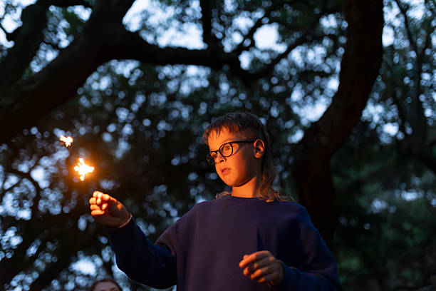 istock Child playing with a sparkler in a forest at twilight 2206238296