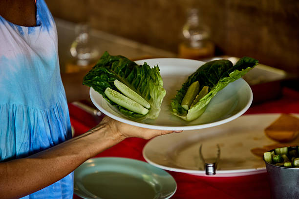 A person holding a plate with fresh salad leaves and cucumber slices, creating a light and healthy meal. The scene exudes a fresh and natural feeling, emphasizing simple dining and healthy living.