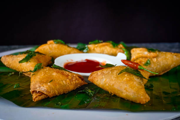 Image of Sri lankan fast food / crispy samosas on banana leaf with tomato sauce, ketchup for dipping