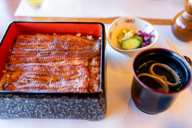 istock Japanese unagi donburi set featuring grilled eel with a glossy soy glaze on rice in a lacquered box, served with miso soup and a side of pickled vegetables 2206243980
