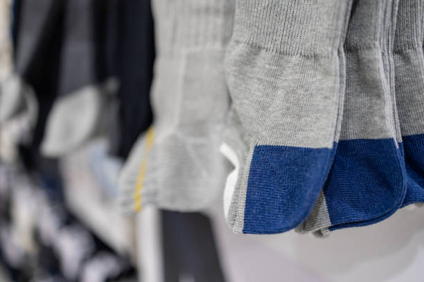 Gray and blue socks with reinforced toe and heel sections neatly displayed on a store rack highlighting soft knitted texture and durable fabric