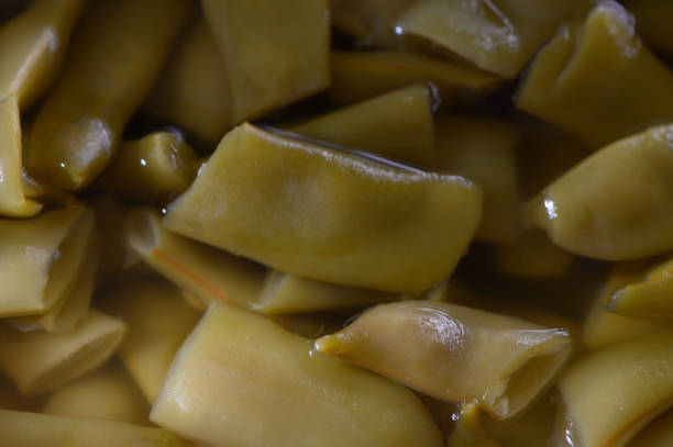 Tender green beans are cut into bite-sized pieces and submerged in a flavorful broth, awaiting their next culinary adventure in a cozy kitchen setting.