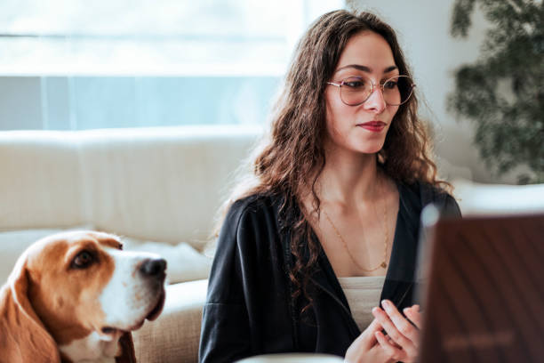 Young woman working at home with her dog by her side