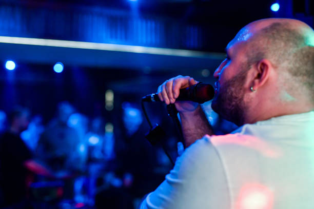 Man Singing on Stage Under Vibrant Lights During a Live Performance