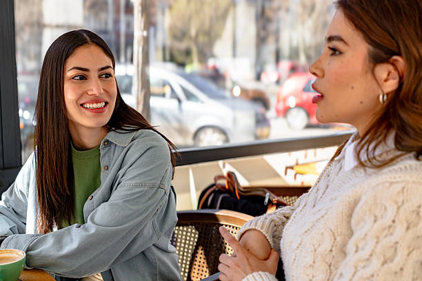 istock Two young women talking and drinking coffee in a bar 2206251118