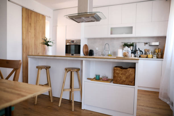 istock Modern white kitchen with island and wooden stools featuring a minimalist design 2206251881