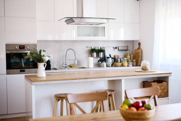istock Modern white kitchen with island and wooden table featuring fresh fruit 2206251893