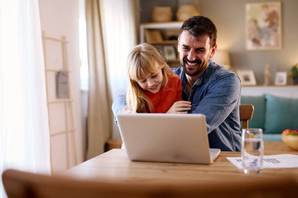 istock Father and daughter laughing while using laptop at home 2206252127