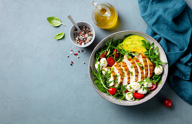 istock Warm grilled chicken salad with avocado and mozzarella cheese. Grey background. Copy space. Top view. 2206252749