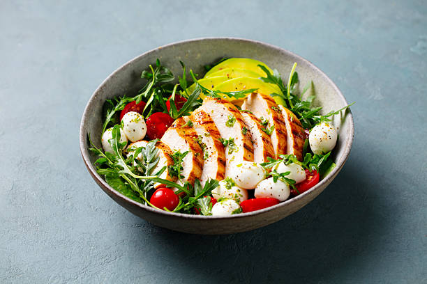 istock Warm chicken salad with avocado and mozzarella cheese. Grey background. Close up. 2206252881