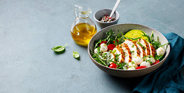 istock Warm chicken salad with avocado and mozzarella cheese. Grey background. Copy space. 2206252935