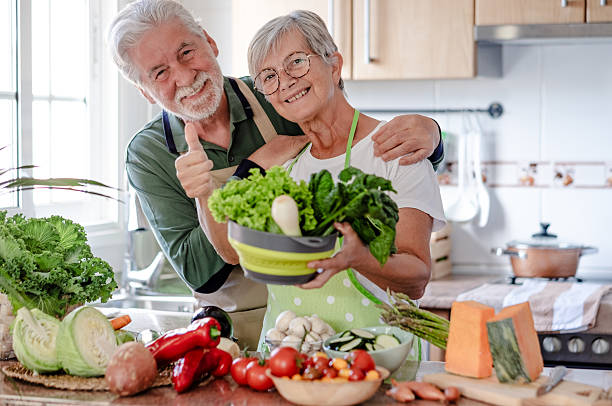 istock Attractive senior couple working together in home kitchen preparing vegetables. Caucasian elderly smiling people retirees enjoying healthy eating looking at camera 2206253294