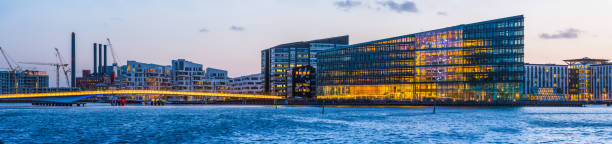 Panoramic view at night across the modern office buildings and apartment blocks along the harbour waterfront in central Copenhagen, Denmark’s vibrant capital city.