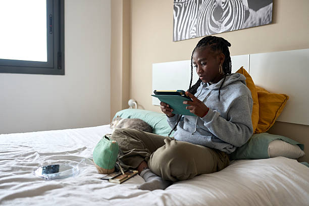 istock Young woman using digital tablet on bed with cat 2206255943