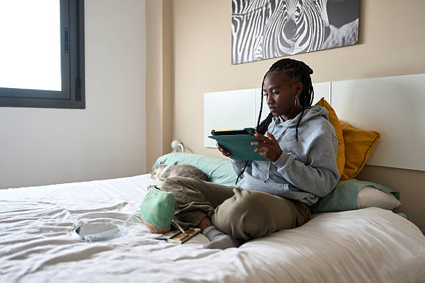 istock Young woman using digital tablet in bedroom with sleeping cat 2206255968