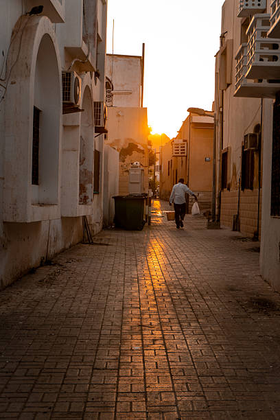 Young man explores streets at sunset, distant view, Oman
