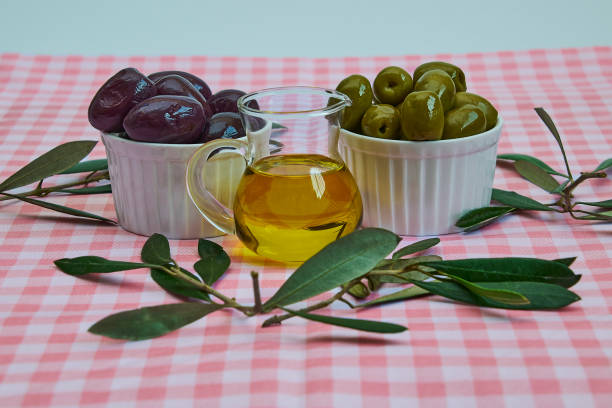 Senior woman's hands reaching for an olive oil cruet and a salt shaker on a white plate, highlighting a traditional home cooking and healthy eating concept