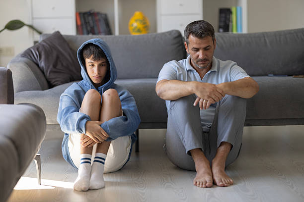 Boy sitting and father on floor appearing to be sad