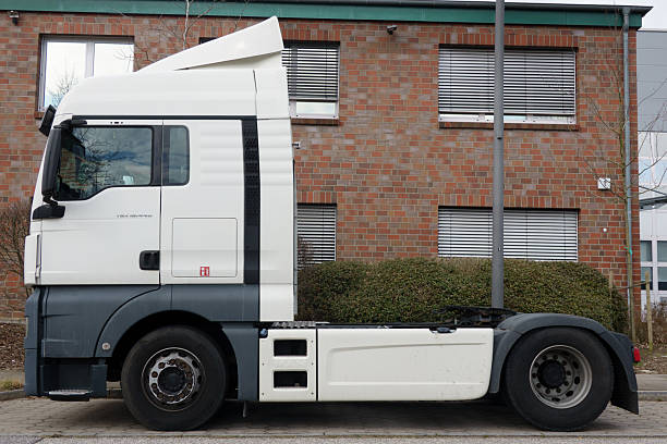 Hamburg, Germany - March 16.2025: White semi-trailer cab without trailer, parked sideways in front of a brick-faced office building in an industrial park in Hamburg