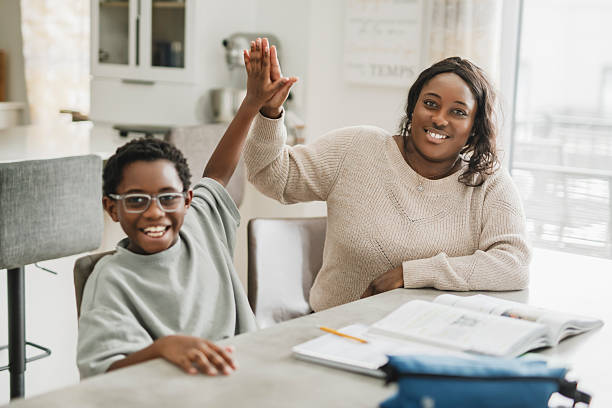istock Beautiful woman and her cute little son doing homework and smiling while sitting on kitchen 2206262264