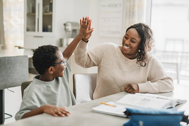 istock Beautiful woman and her cute little son doing homework and smiling while sitting on kitchen 2206262267