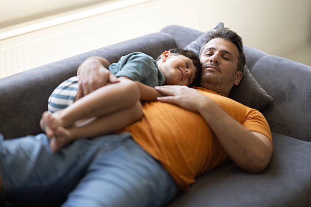 istock Father and son sleeping together on a sofa in living room 2206263841
