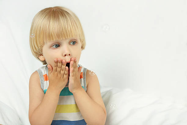 Girl blowing a big bubble gum bubble isolated on blue