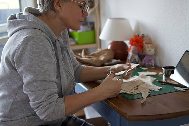istock An elderly woman is making textile dolls 2206266713