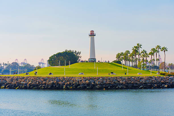 Long Beach, California - January 11, 2025: Lions Lighthouse for Sight stands majestically on a grassy hill, surrounded by palm trees, with a peaceful shoreline view of Shoreline Marina, capturing daytime tranquility.