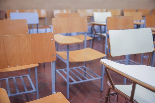 Quiet classroom with neatly arranged wooden chairs and desks. A well-organized, functional learning environment, ready for educational activities.