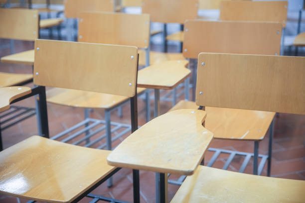 Quiet classroom with neatly arranged wooden chairs and desks. A well-organized, functional learning environment, ready for educational activities.