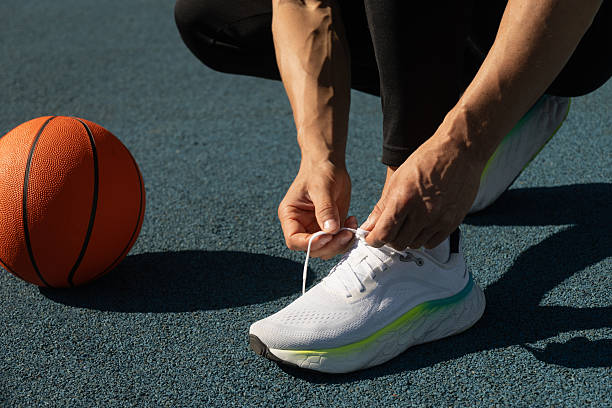 istock Basketball player tying running shoes shoelace before training. 2206273374