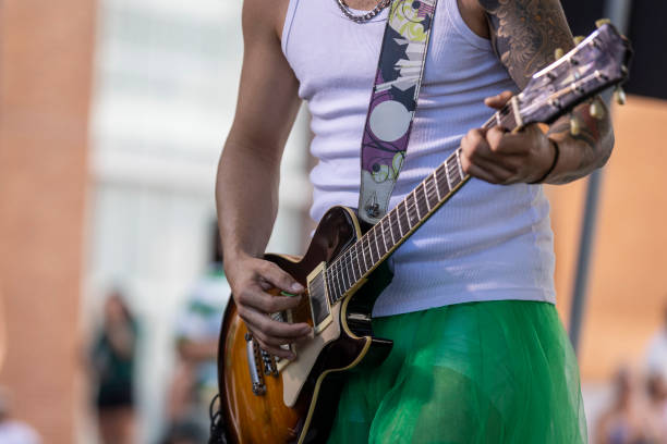Beautiful active senior woman skateboarding at skate city park and playing guitar - Cheerful mature adult female having fun singing, concepts about elderly, modern lifestyle and leisure time