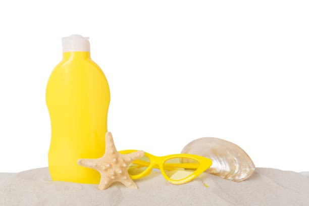 Sunscreen lotion with summer decor on sand against isolated background
