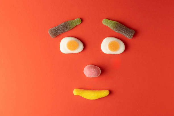 istock Funny face created with colorful gummy candy on red background 2206277116