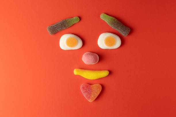 Funny face created with colorful gummy candy on red background
