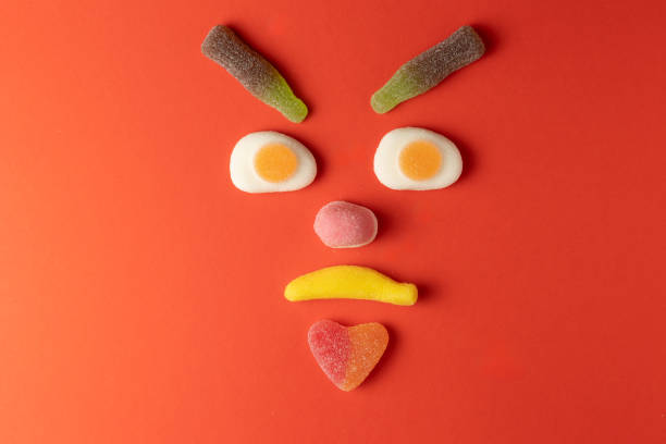 istock Grumpy face made of colorful gummy candy on red background 2206277125