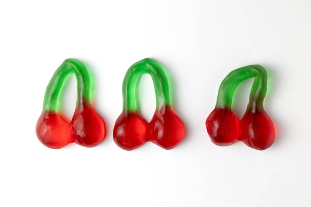 Three cherry shaped gummy candies on white background