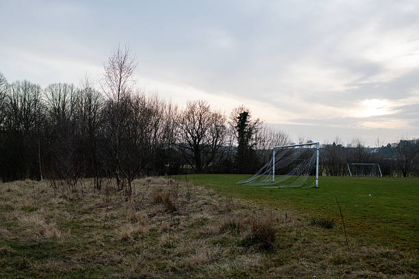 Eyam A soccer field with a goal and a few trees in the background. The sky is cloudy and the grass is dry
