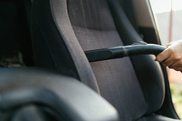 istock Man Vacuuming Car Seat Interior with Vacuum Cleaner in Sunlight 2206281162